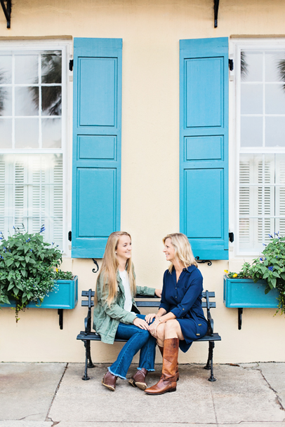 Portraits of mother and daughter by yellow home with blue shutters in Charleston, SC