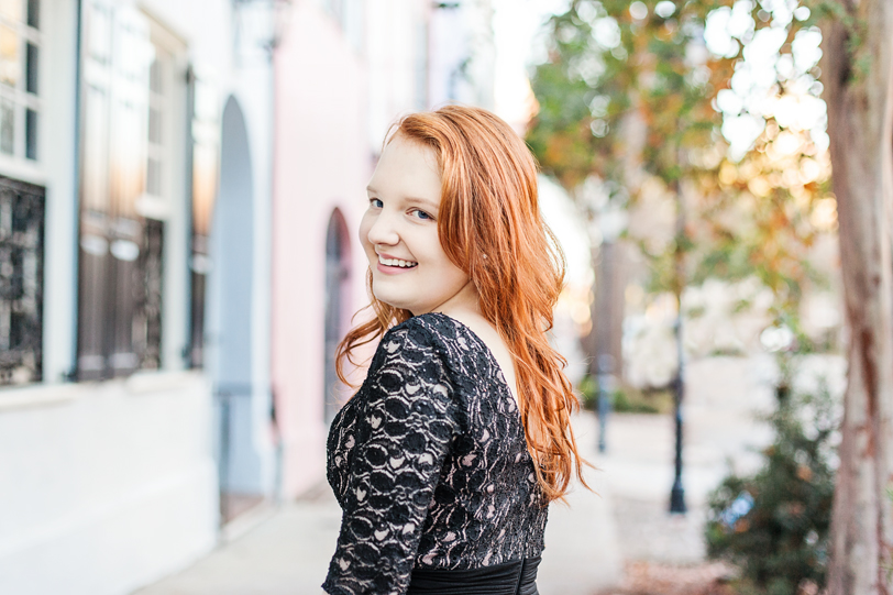 Smiling Senior girl with red hair in front of colorful Rainbow Row, Portraits by Kaitlin Scott Photography