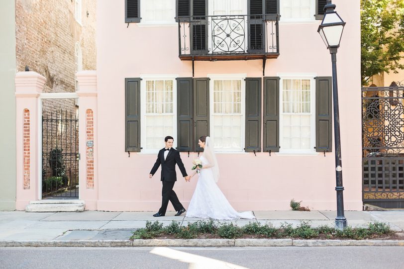 Groom leads Bride down Meeting Street by Pink Charleston House | Kaitlin Scott Photography