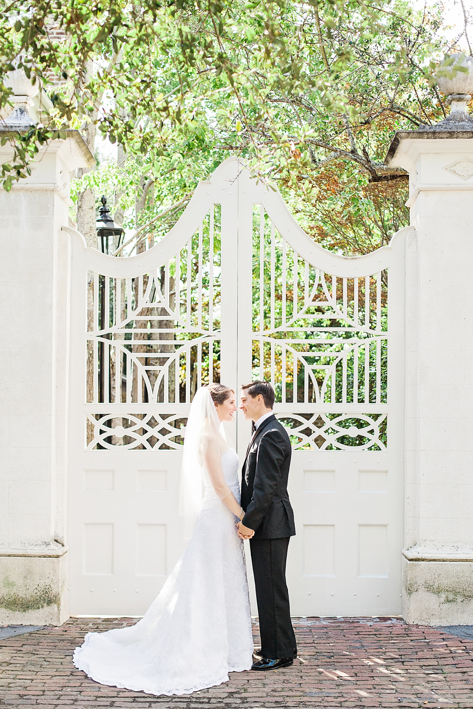 Newlyweds holding hands by white Charleston gate | Kaitlin Scott Photography