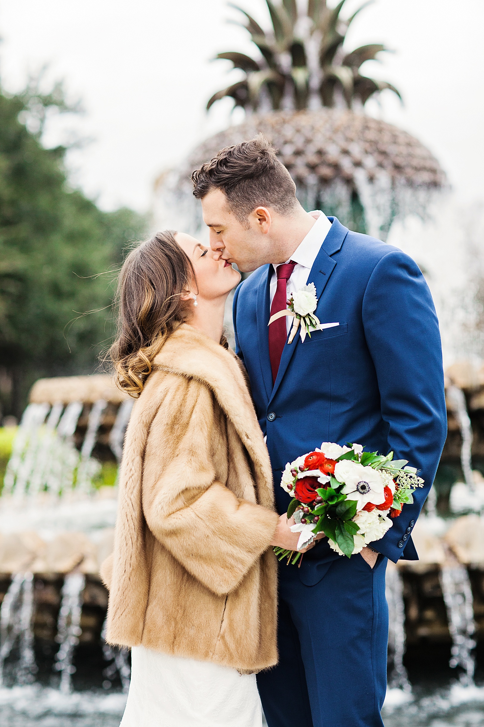 Christmas Bride and Groom share a kiss at Pineapple Fountain in Charleston | Kaitlin Scott Photography