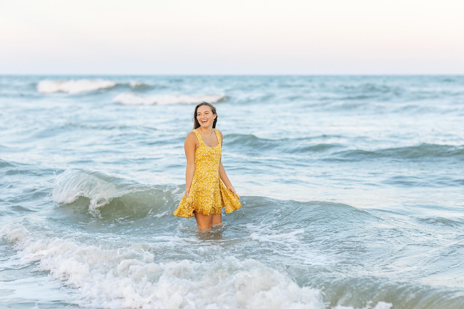 Girl in yellow dress in ocean at sunset