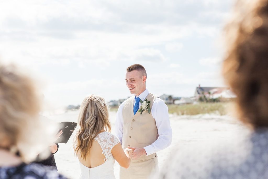 Groom looks at bride at wedding at the beach